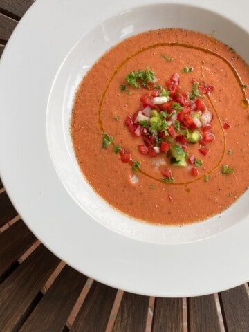 A bowl of Tomato soup sitting on top of a wooden table.