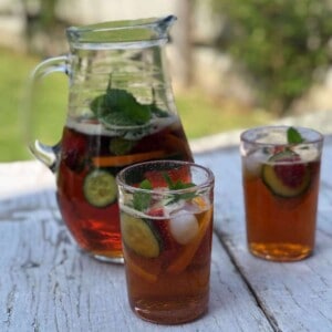 A jug of pimms and two glasses on a table.