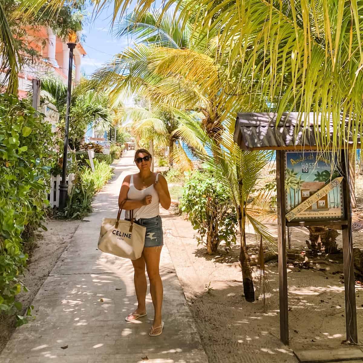 A person walking down a sidewalk next to a tree