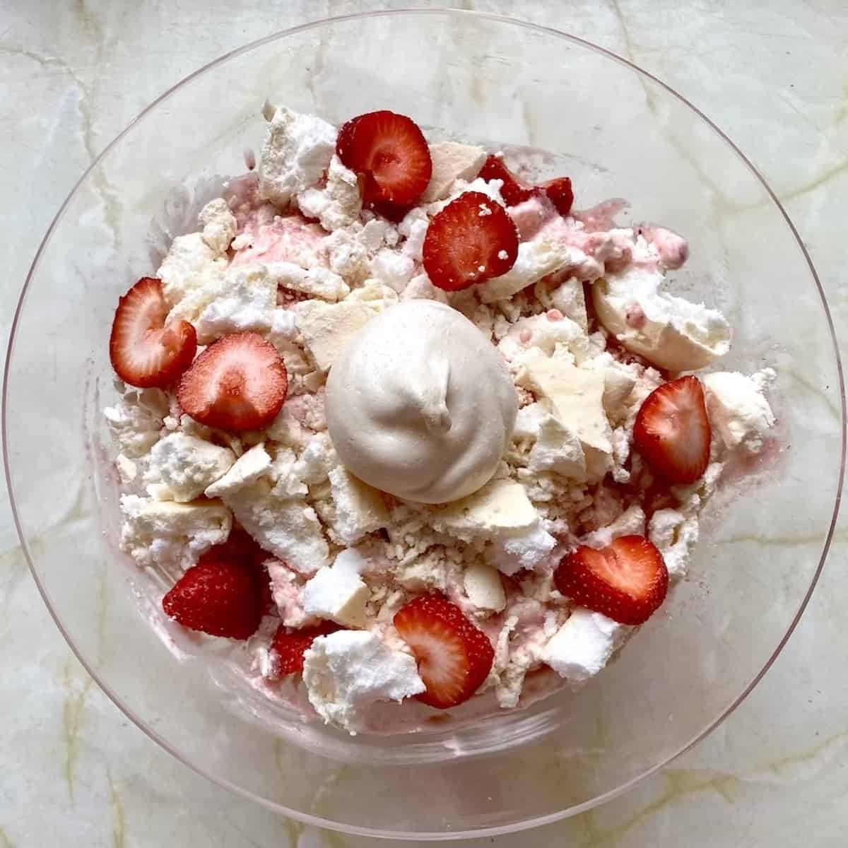 A bowl of Eton mess with fresh strawberries, cream and meringue.