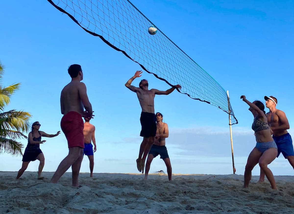 A group of people playing a game of volleyball. 
