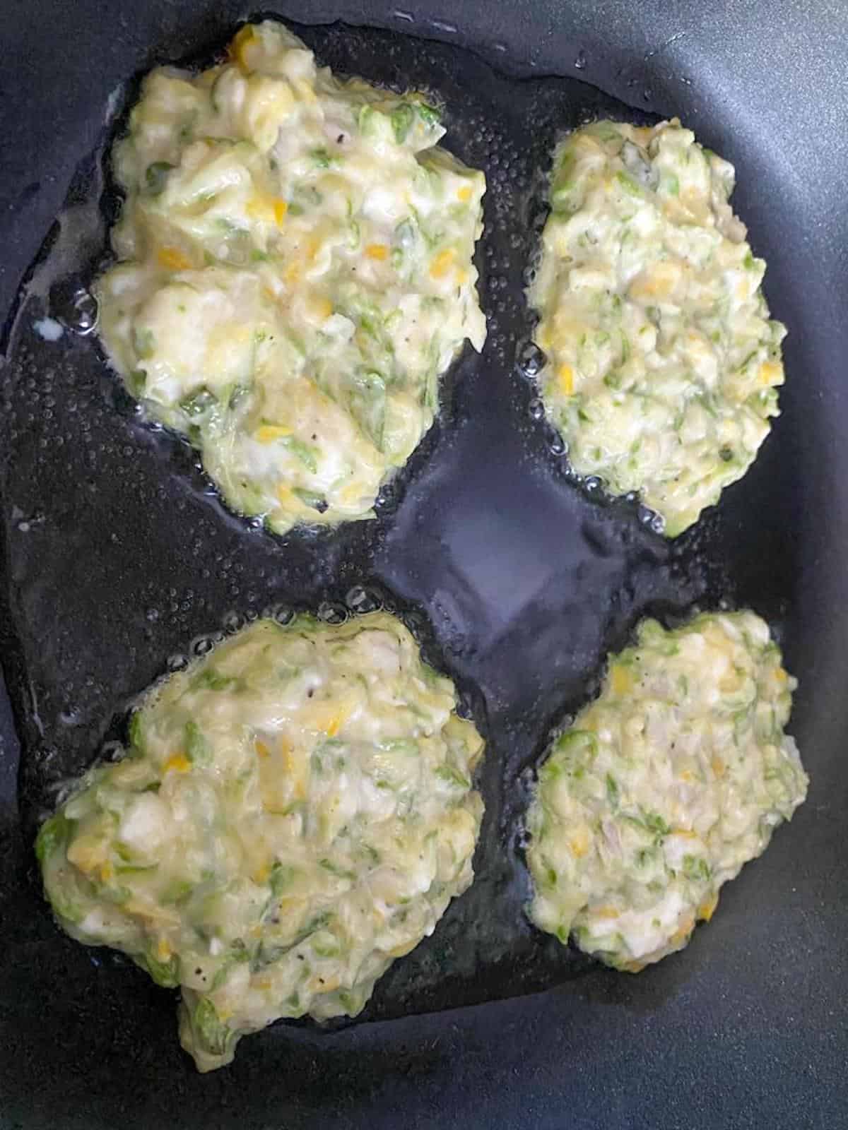 frying the courgette feta fritters in oil 
