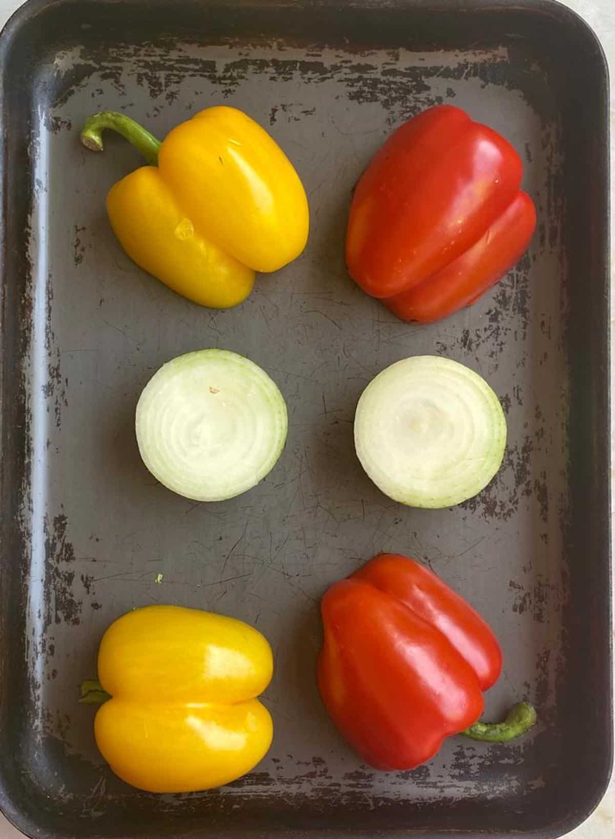 peppers and onion on a baking tray ready to be roasted 