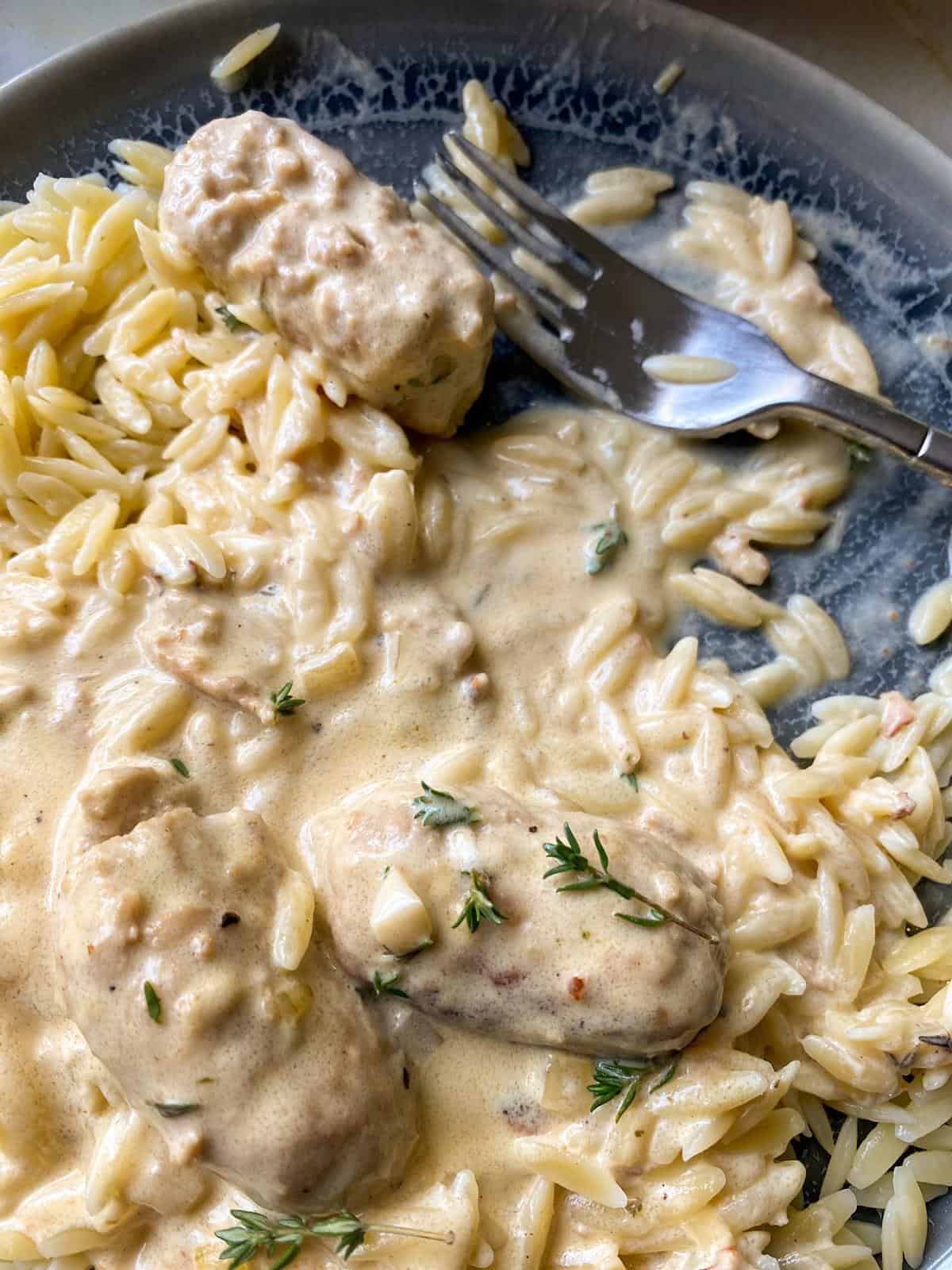 a plate full of warm orzo smothered in a creamy mustard sauce and sausage meatballs 
