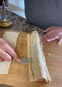 Crimping the edges of the puff pastry with a fork to keep it together