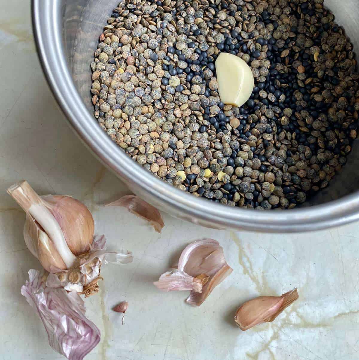 Lentils in a saucepan with a clove of garlic to add flavour 