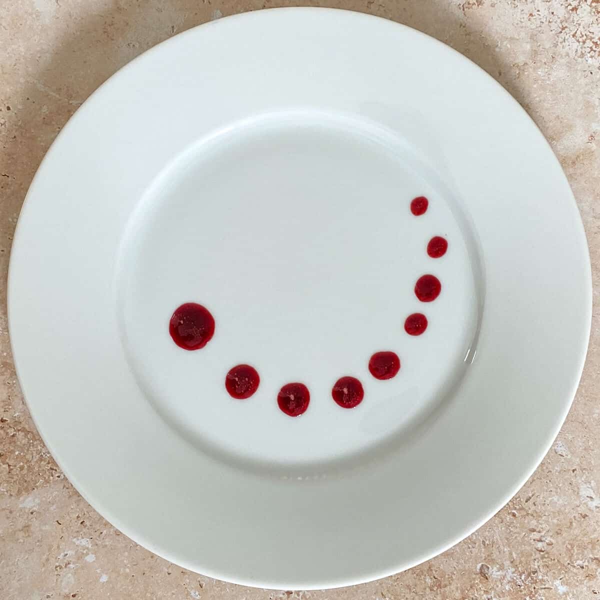 A plate with spots of sauce on it, showing a plating technique for sauce 
