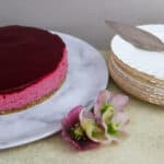 A blackcurrant Mousse Cake with a stack of dessert plates