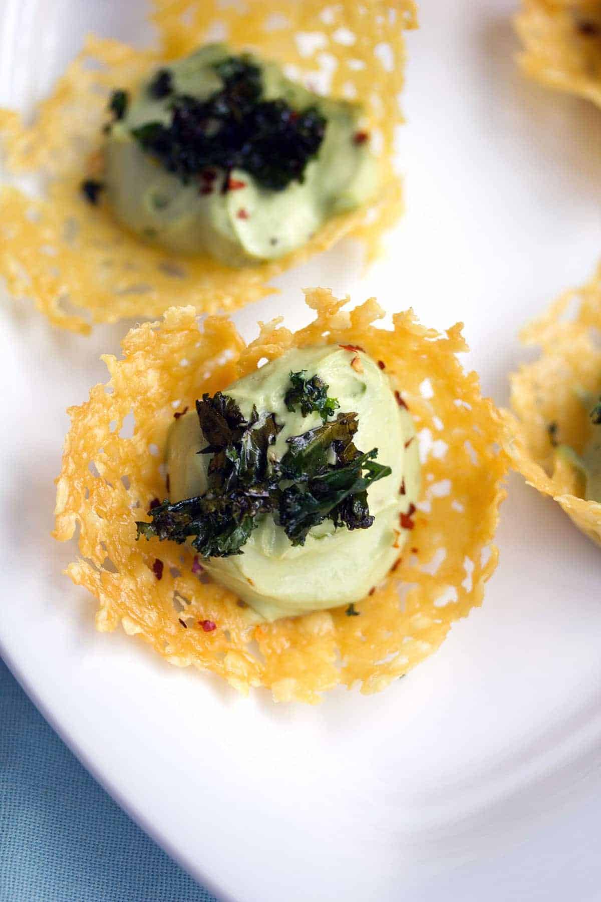 A delicate cheddar cup canapé with avocado feta mousse on a serving dish 