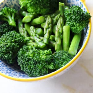 a bowl of cooked broccoli and asparagus
