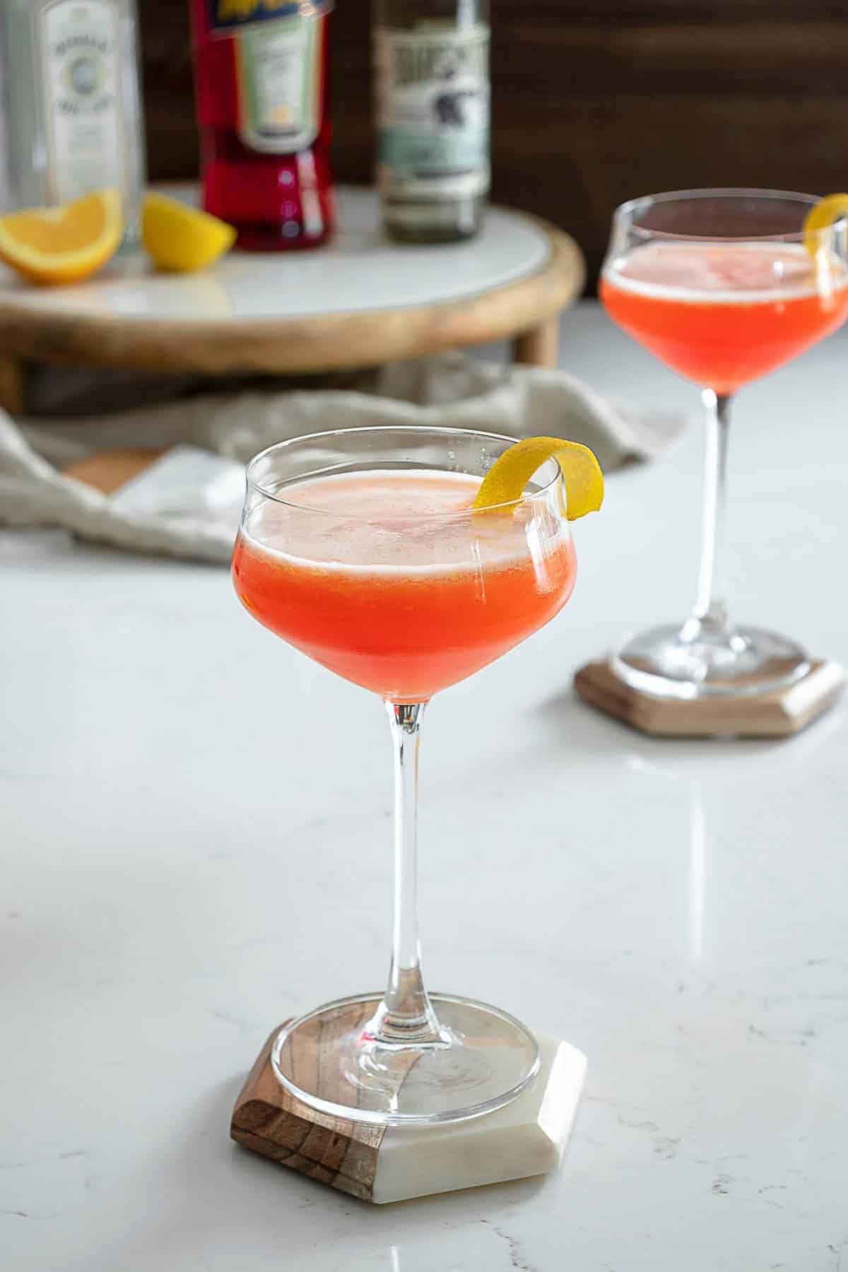 classiest cocktails - a gin aperol sour in a fine stem cocktail glass 