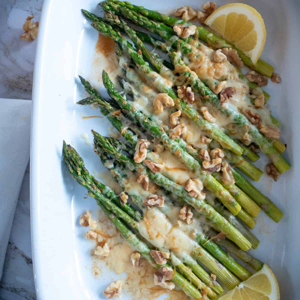 Spears of asparagus covered in melted gouda and walnuts 