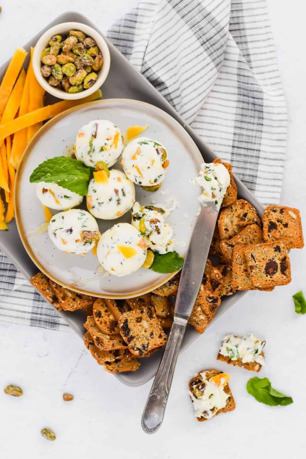 Canapés made from goat cheese, nuts and herbs formed into a ball on a serving platter