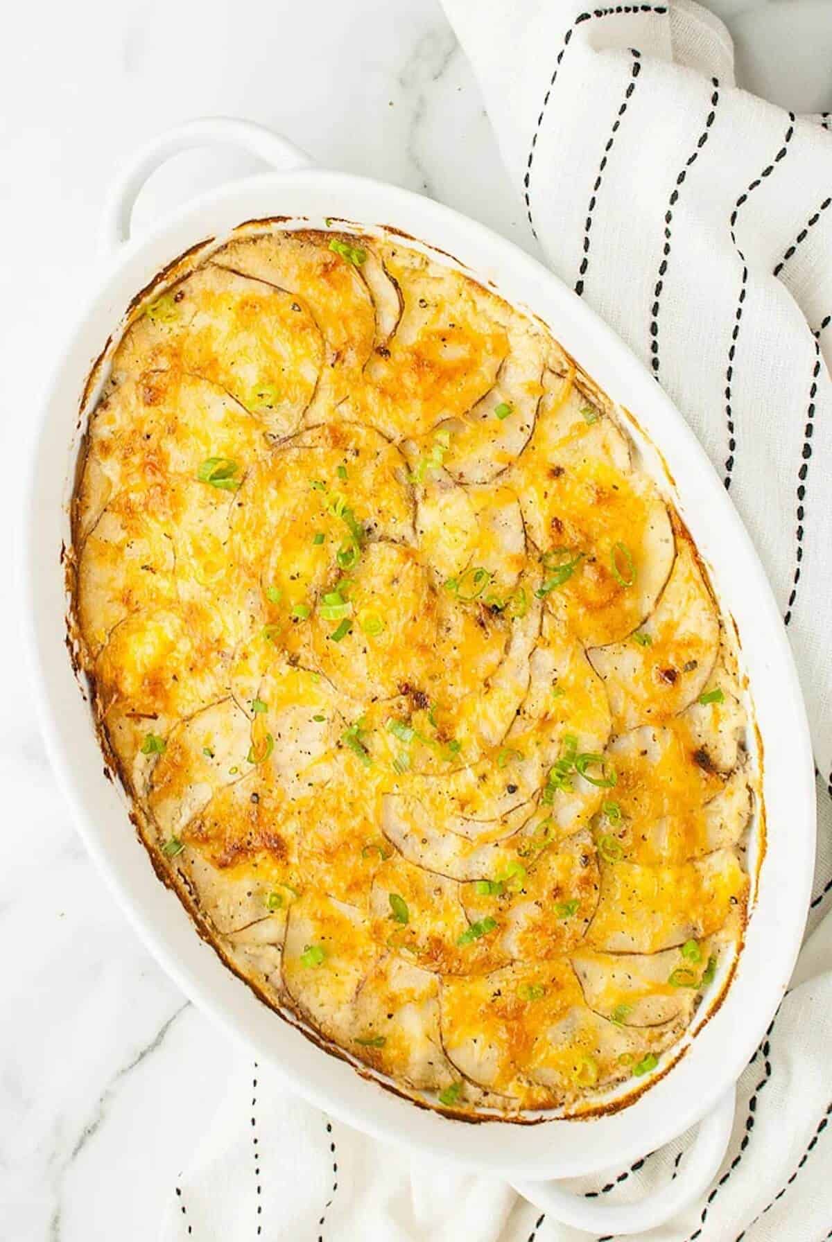 A large oval dish with cheesy scalloped potatoes 