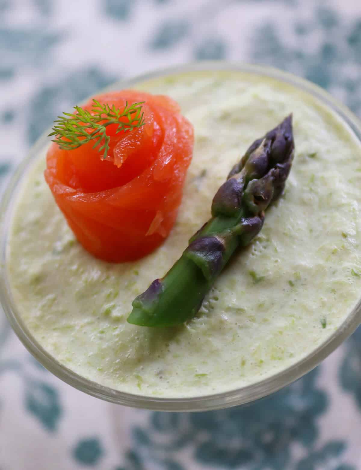 asparagus mousse in a serving glass with smoked trout shaped into a rose and a spear of asparagus.