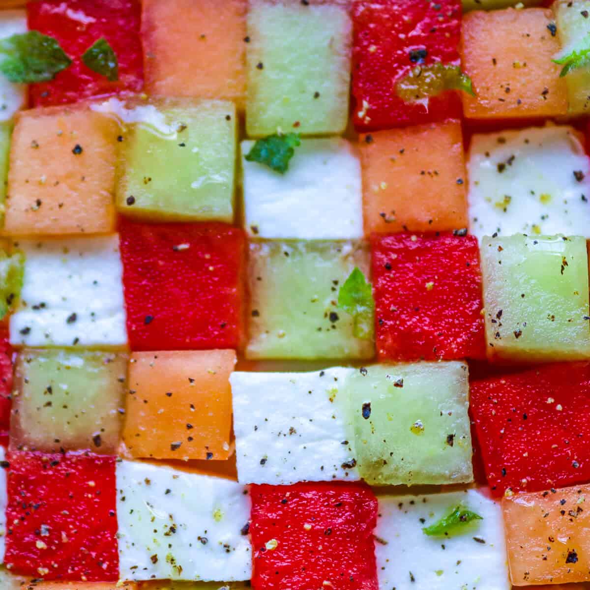cubes of watermelon, cantaloupe lemon and gala melon with cubes of feta cheese in a chequerboard pattern