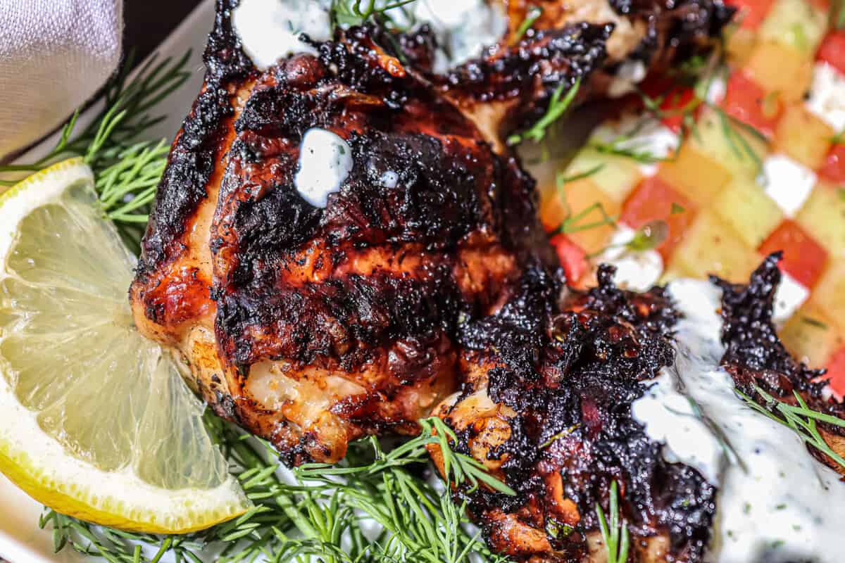 A BBQ'd chicken drumstick with fresh dill and a slice of lemon.