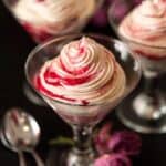 Martini glasses filled with white chocolate cheesecake, shot through with raspberry compote ribbons.