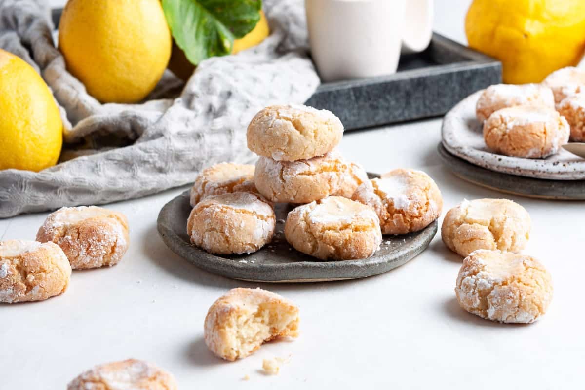 Lemon and almond biscotti on a plate surrounded by lemons.