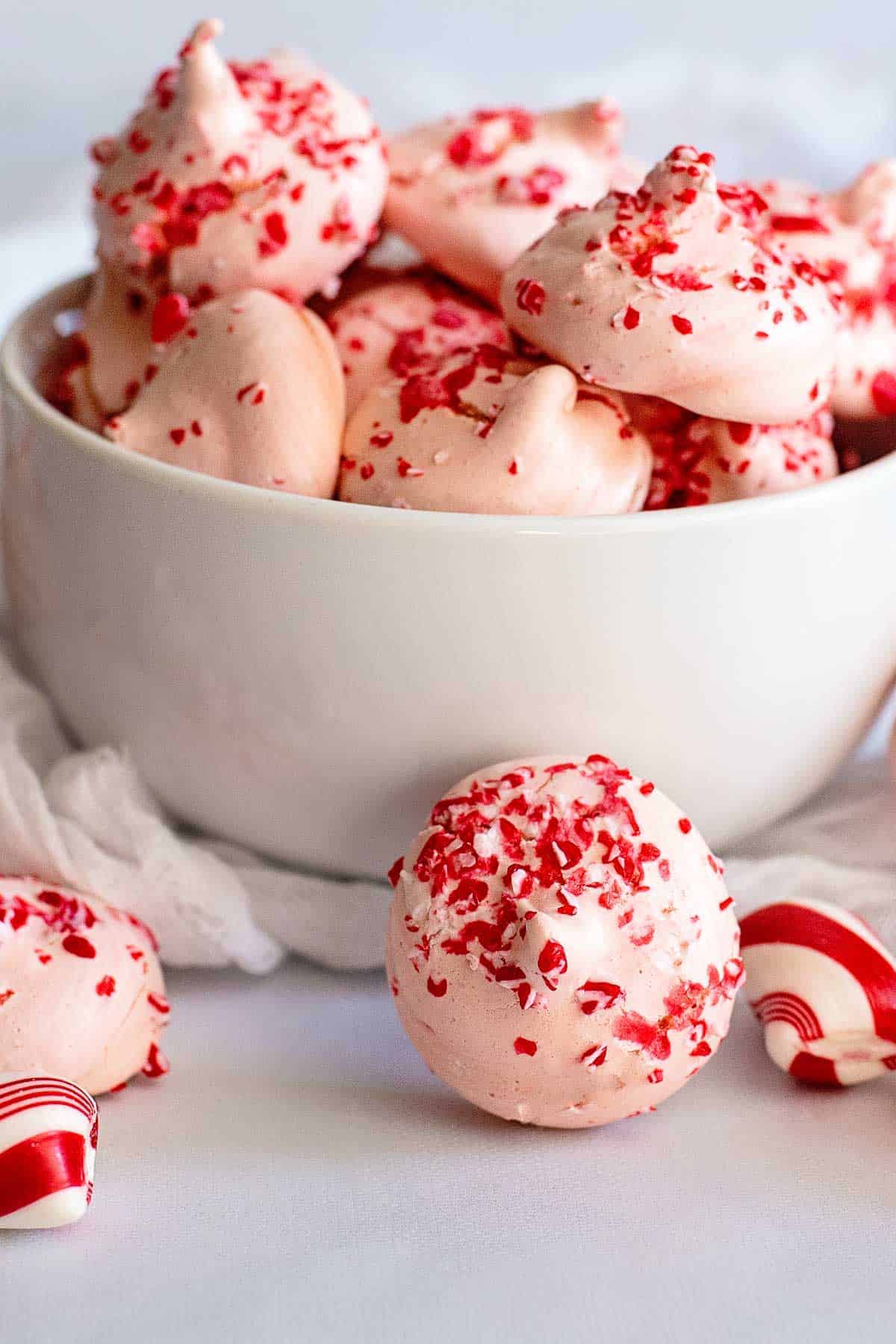 Pink and white peppermint meringues in a bowl.