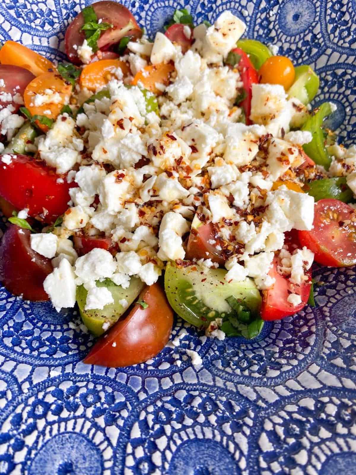 Heirloom tomato salad in a bowl with feta cheese and hot honey dressing. 