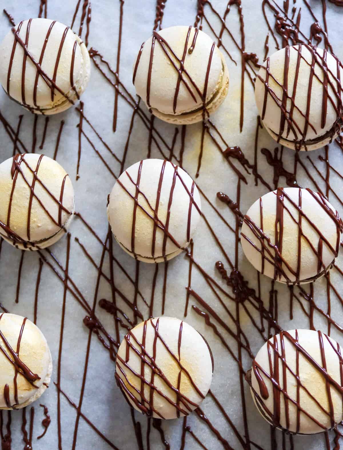 Macarons decorated with piped chocolate.