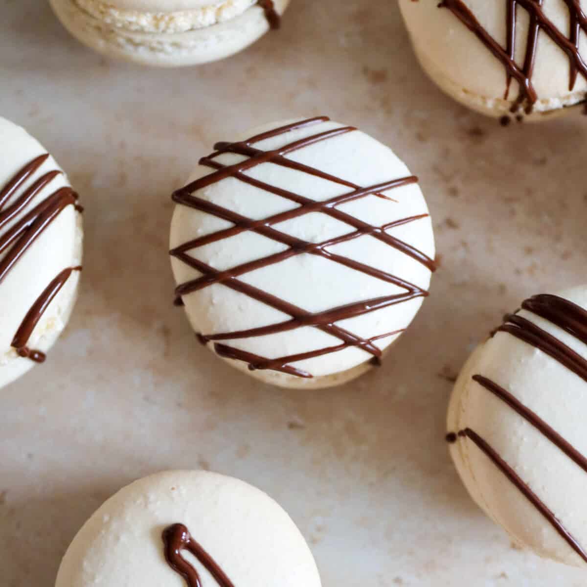 Chocolate cinnamon fall macarons on a table.