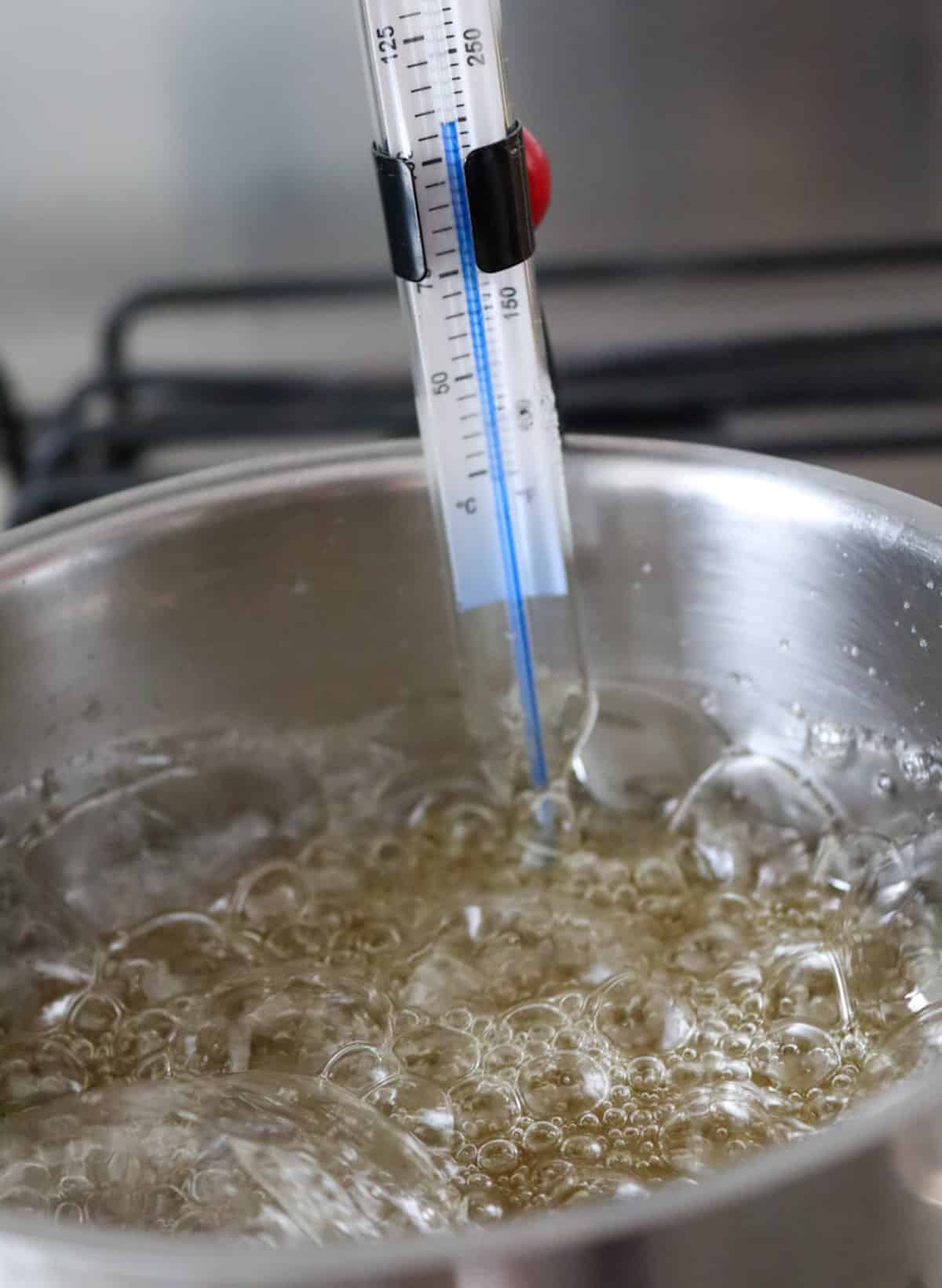 Boiling sugar syrup in a saucepan with a thermometer in it to measure the temperature.