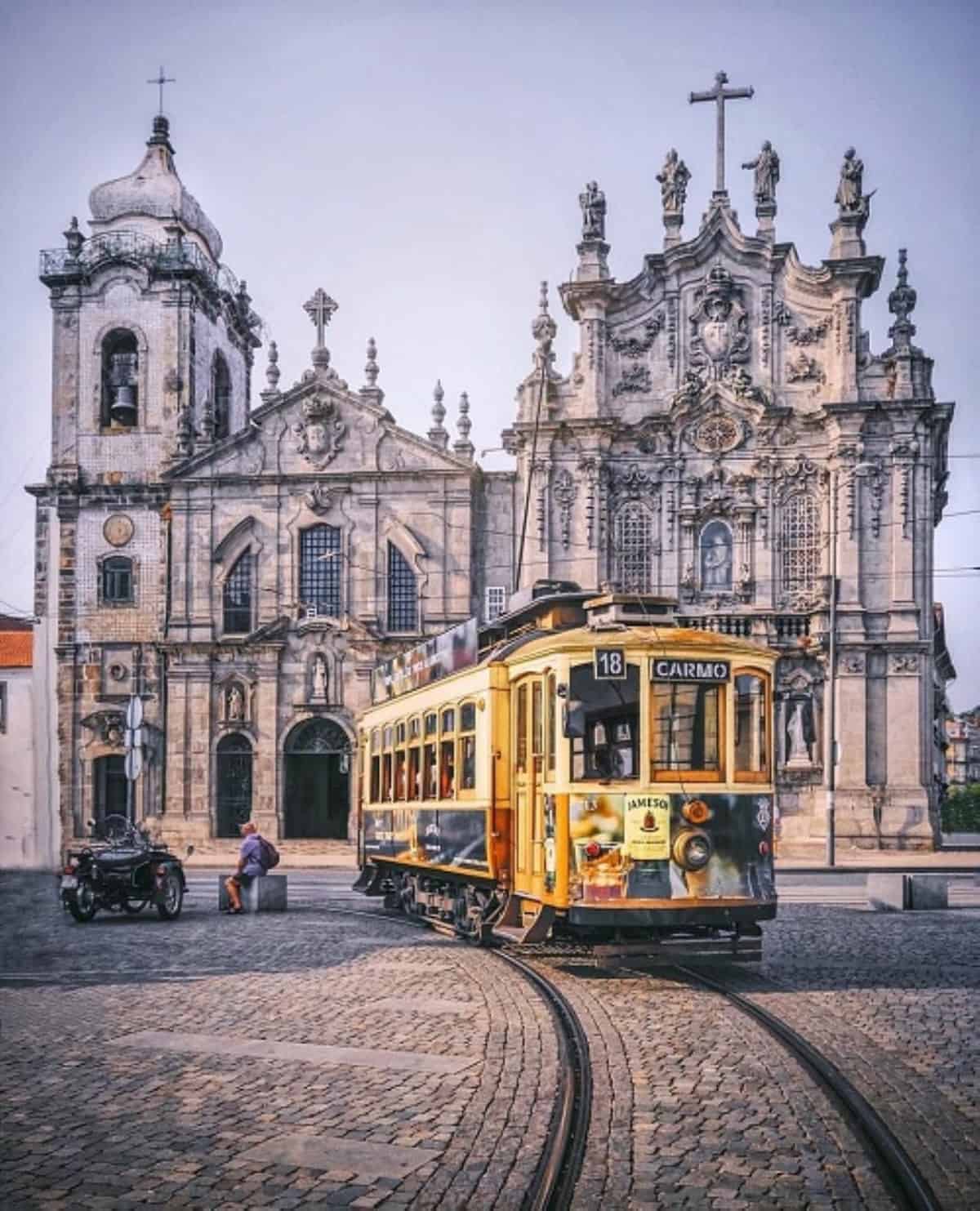 A tram in Porto, Portugal in front of an ornate building. 