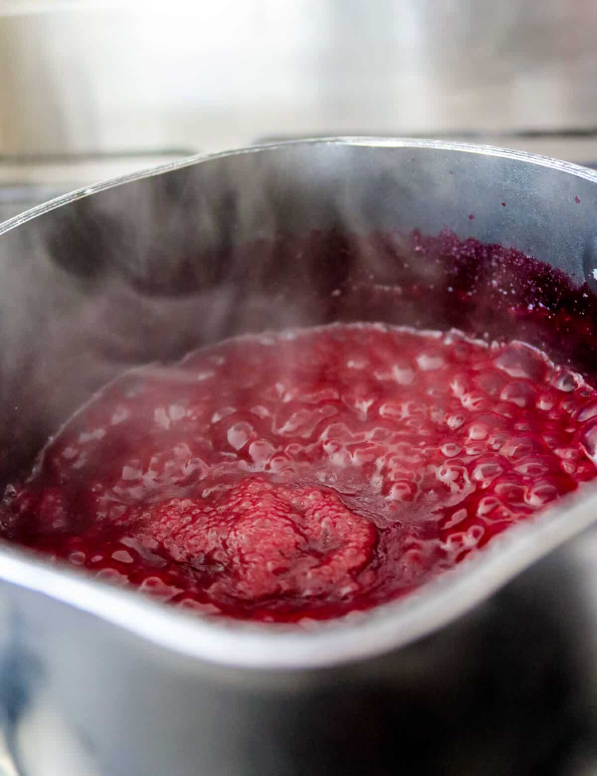 Blueberry puree bubbling in a saucepan.