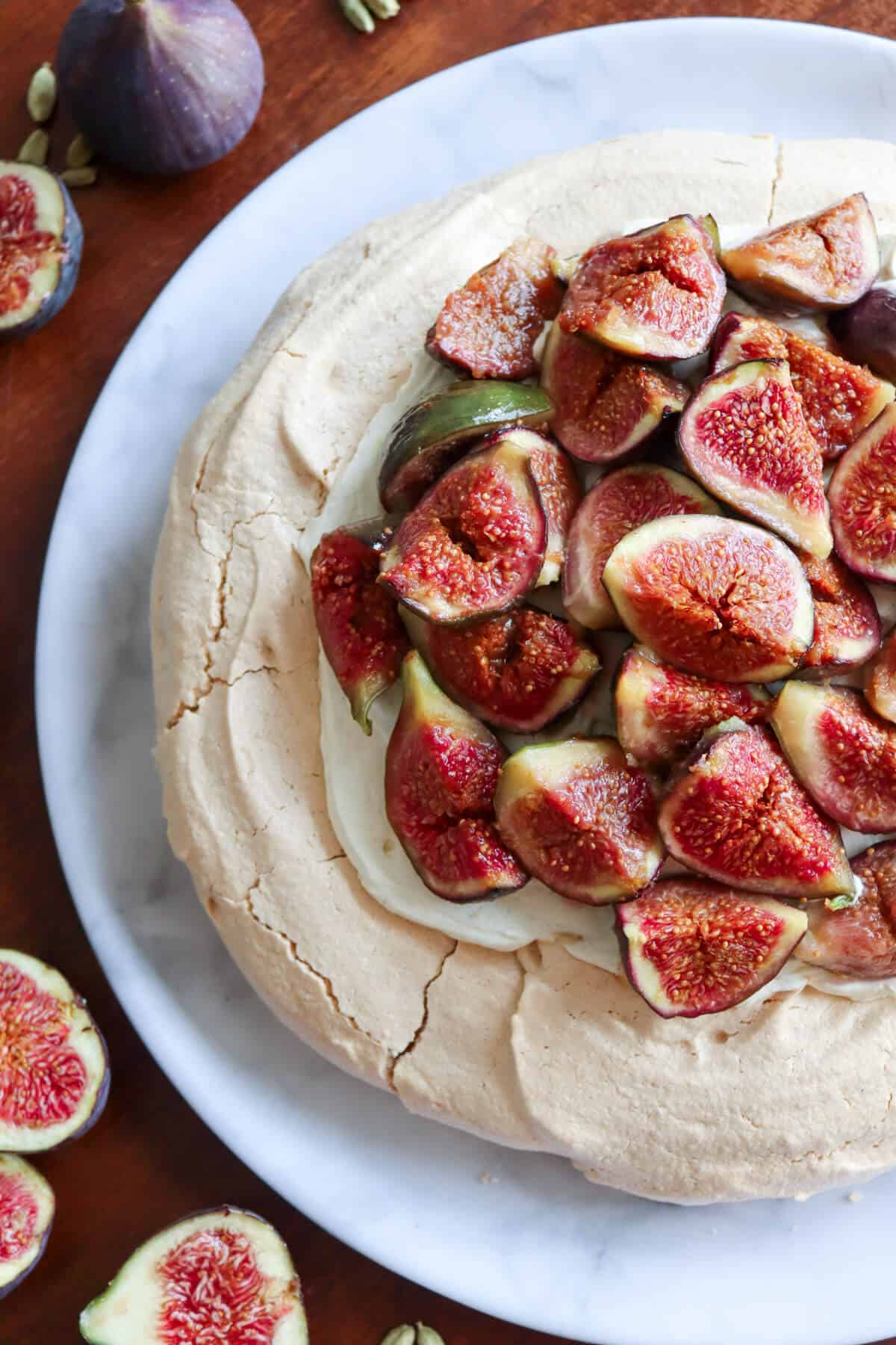 A fig and cardamom pavlova surrounded by fresh figs. 