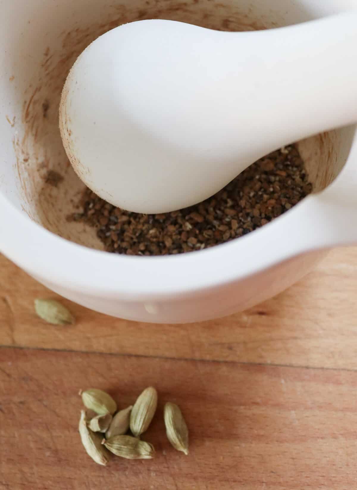Cardamom seeds in a pestle and mortar being ground down. 