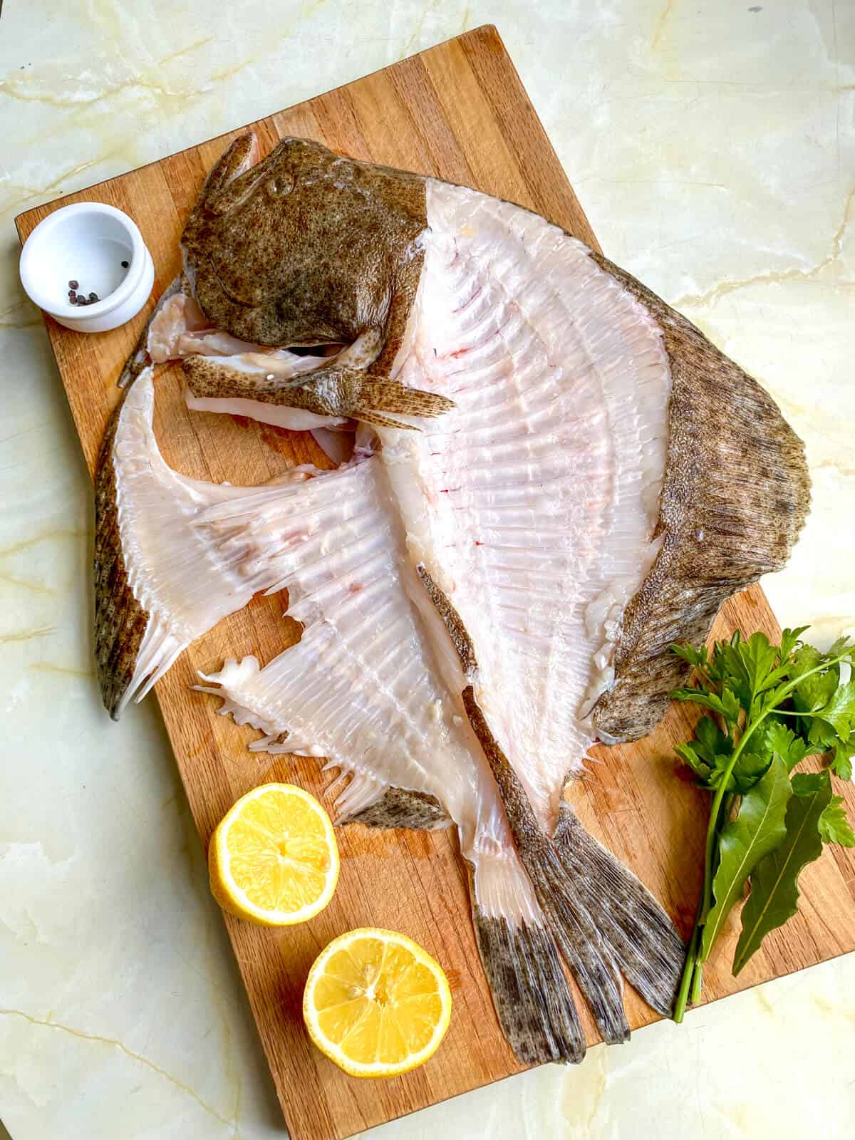 The ingredients for fish stock: fish bones, peppercorns, herbs and lemon. 