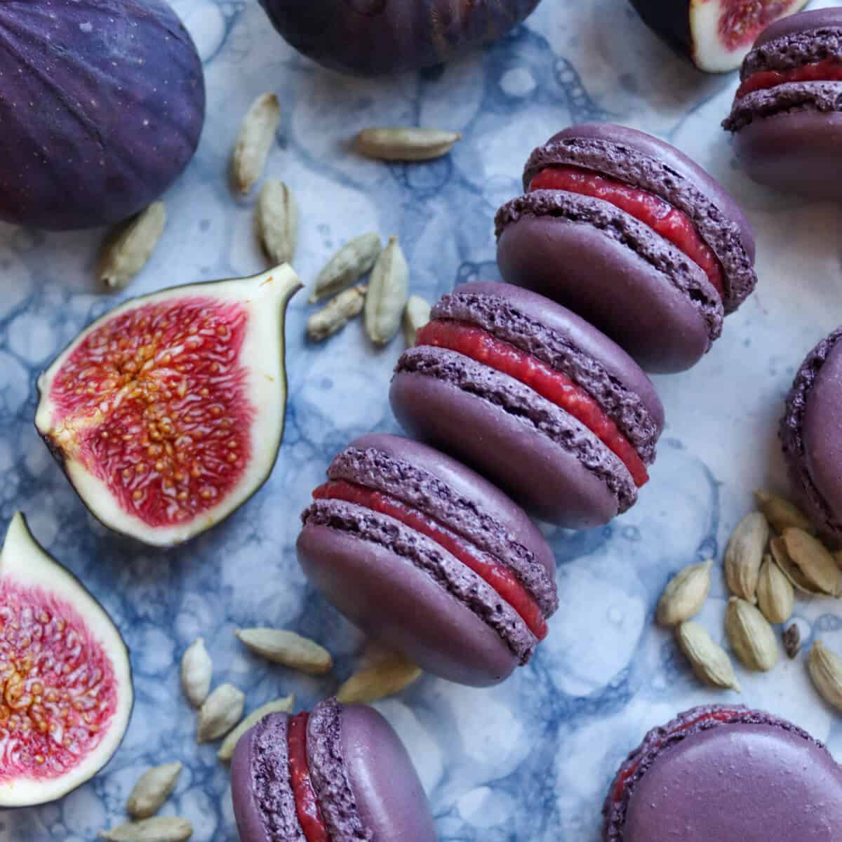 Fig and Cardamom fall macarons on a plate with fresh figs.