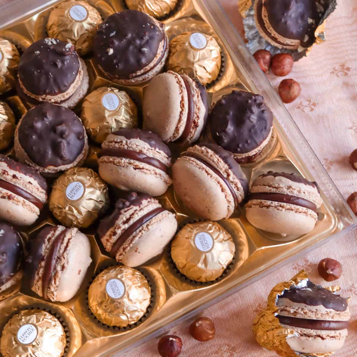 A gold chocolate box tray filled with macarons and Ferrero Rocher chocolates.