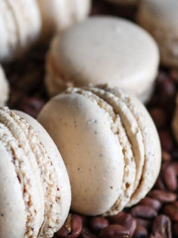Hazelnut coffee macarons on a bed of coffee beans.