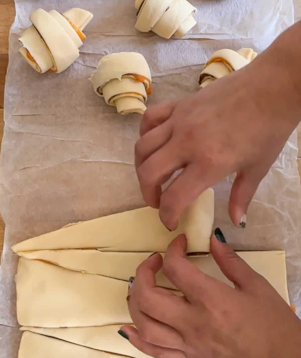 Rolling croissants from triangles of puff pastry.