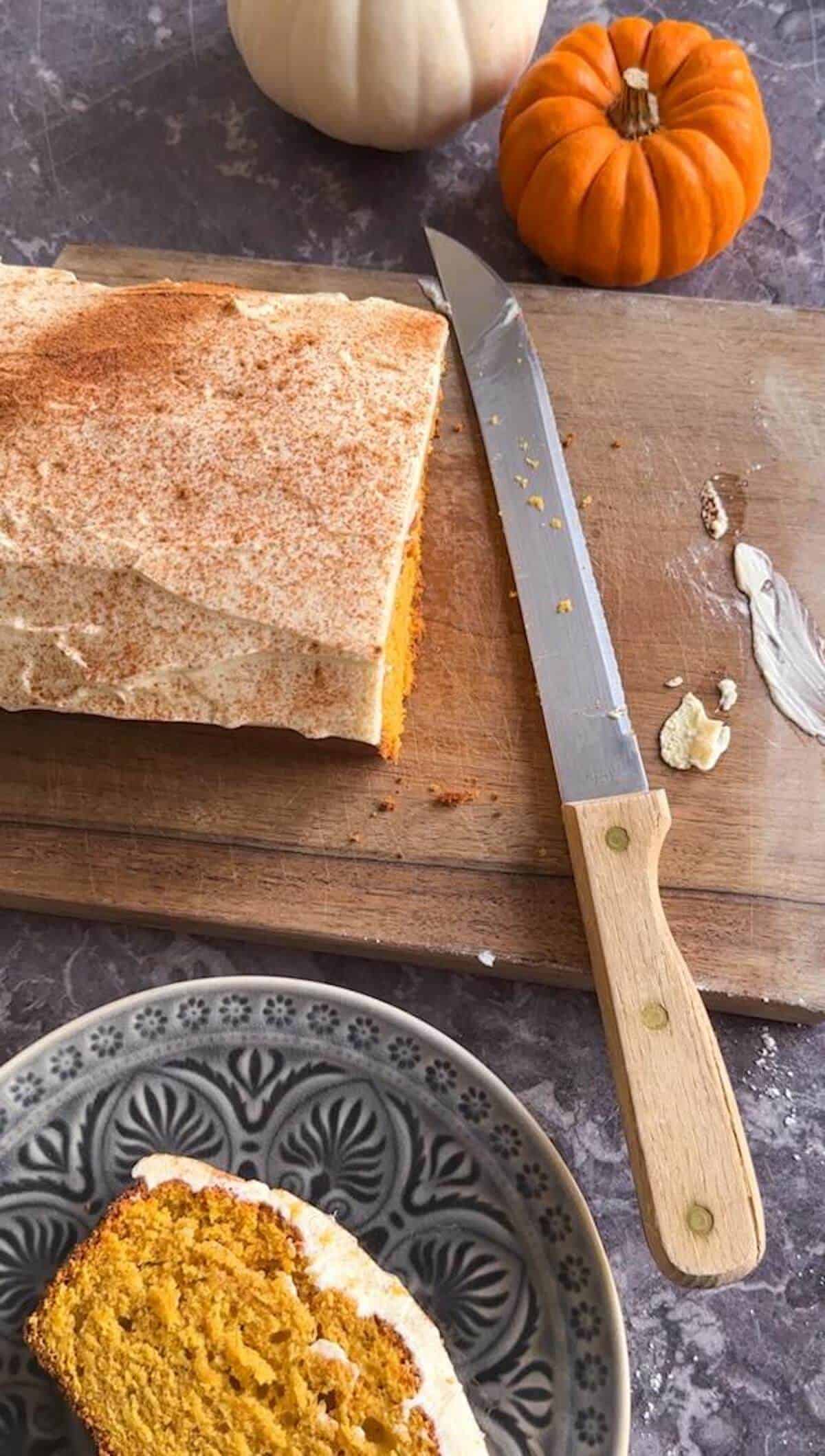 A bread board with pumpkin yogurt cake on it, and a plate with one slice.