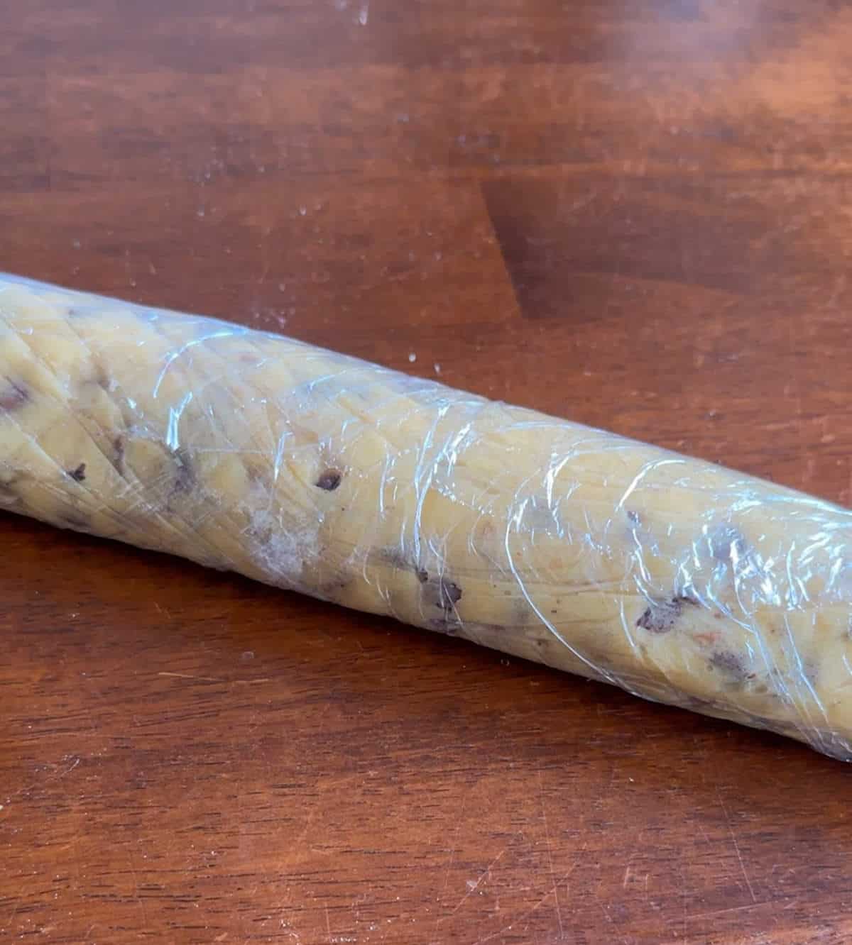 A log of cookie dough rolled up in plastic food wrap to be chilled. 