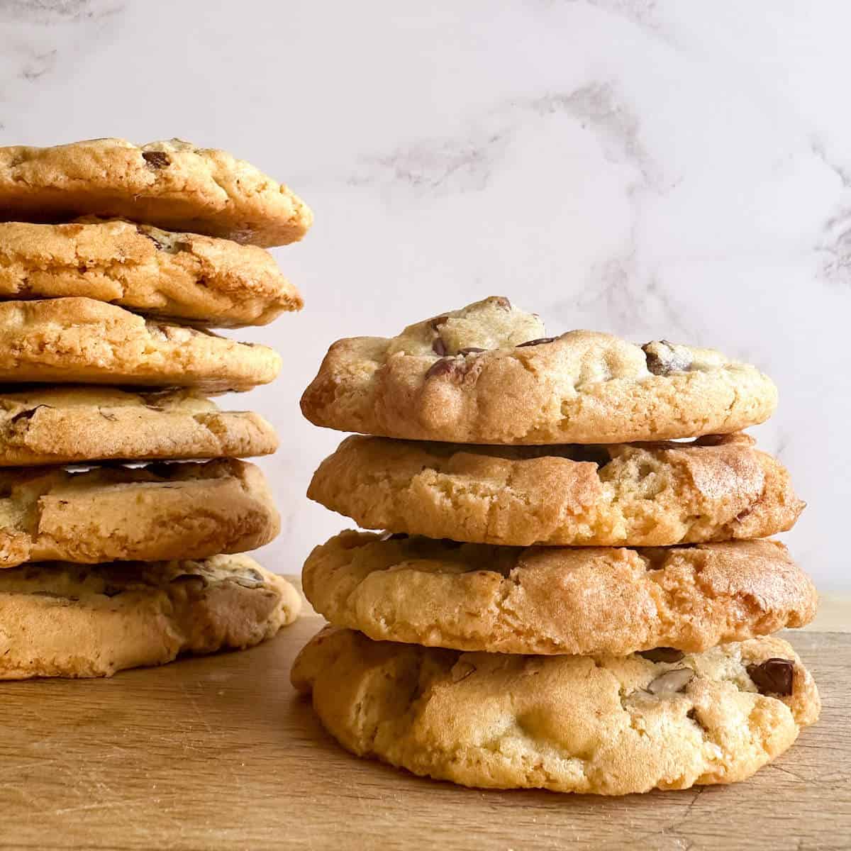Two stacks of cookies on a chopping board.