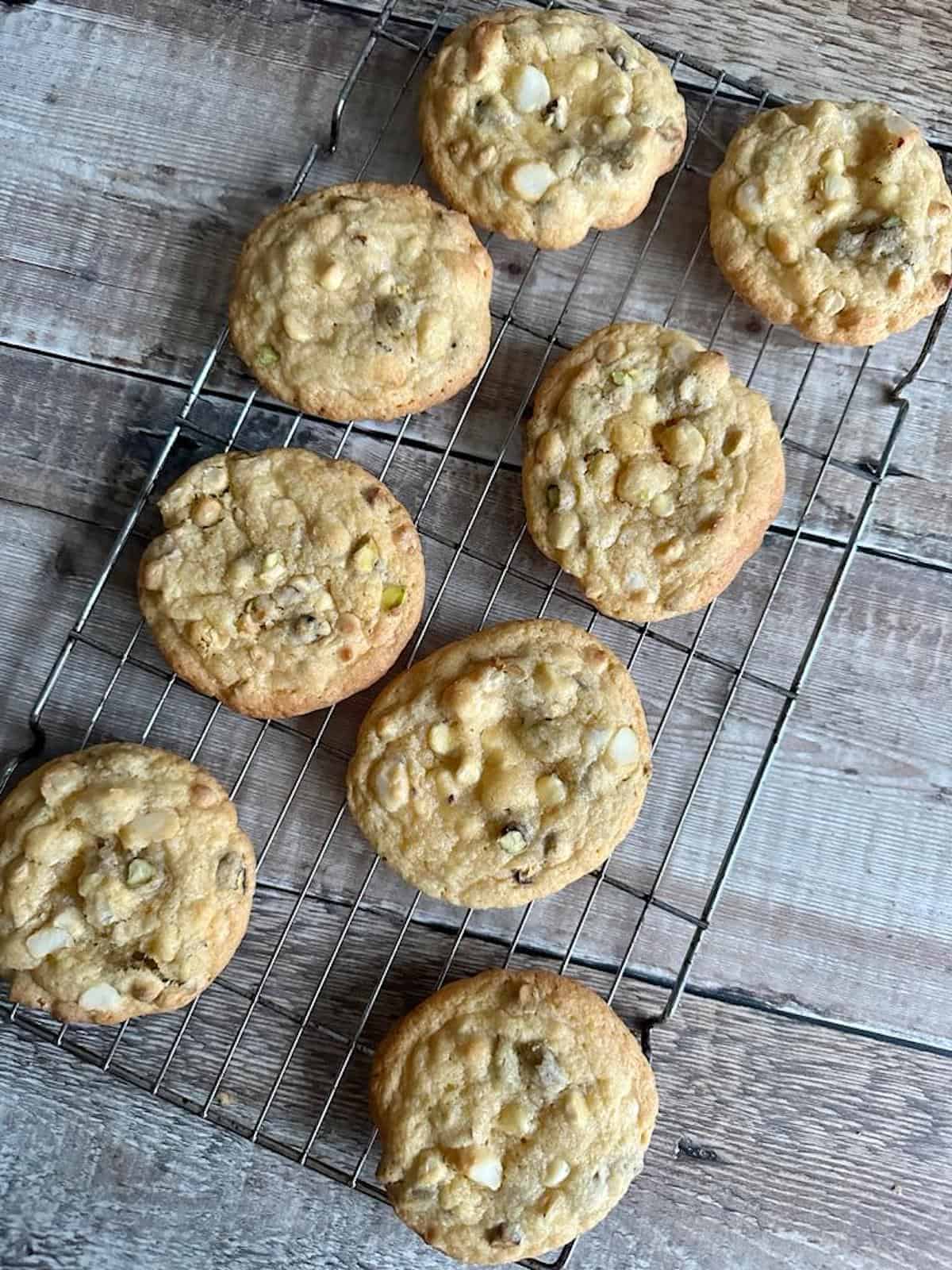 Freshly baked pistachio, white chocolate and macadamia nut cookies on a cooling rack. 