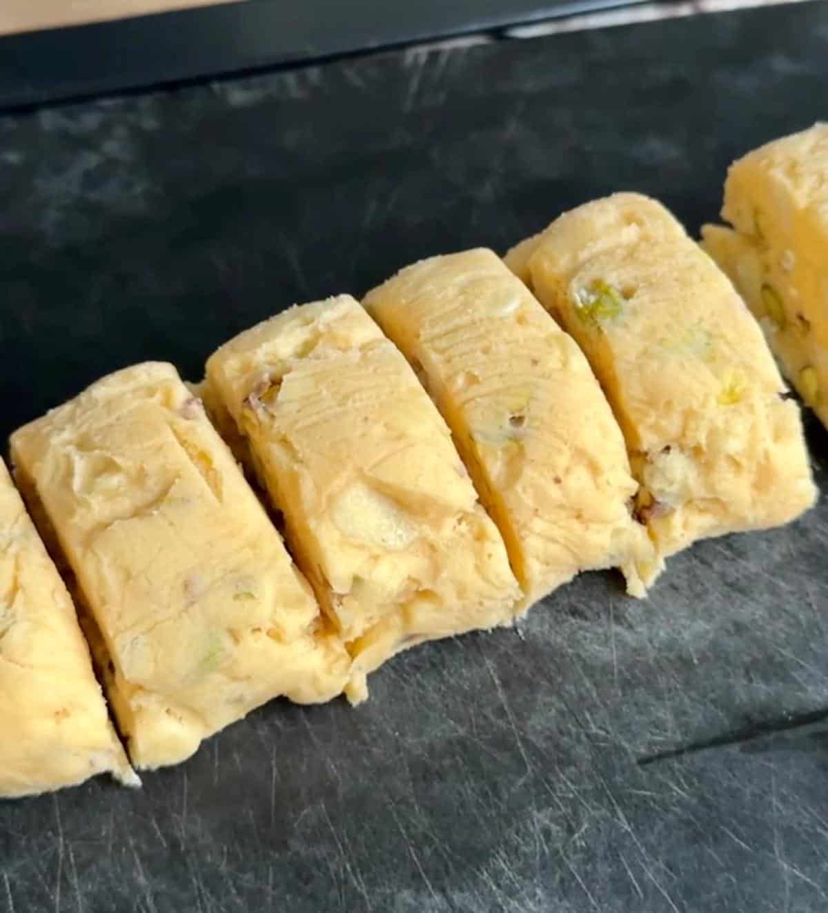 Cookie dough formed into a log and sliced into pieces ready to be baked. 