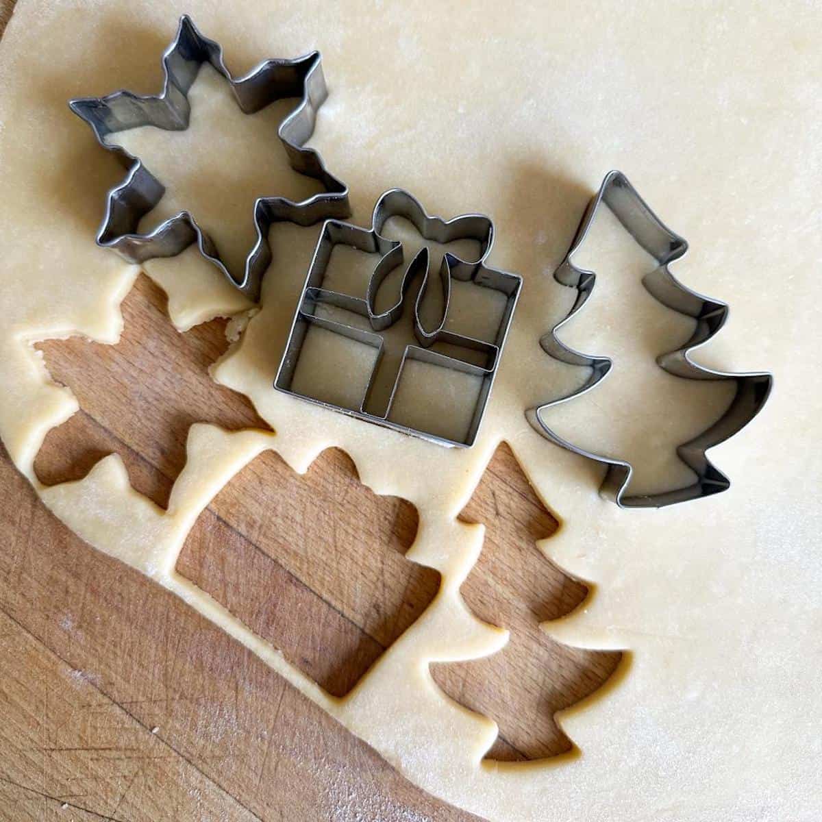 Christmas cookie cutters and a piece of pastry rolled out on a worktop. 