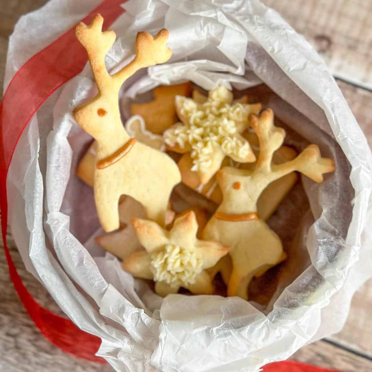 Sweet shortcrust pastry cookies in Christmas shapes including reindeer, Christmas tree, presents and stars in a cookie tin. 
