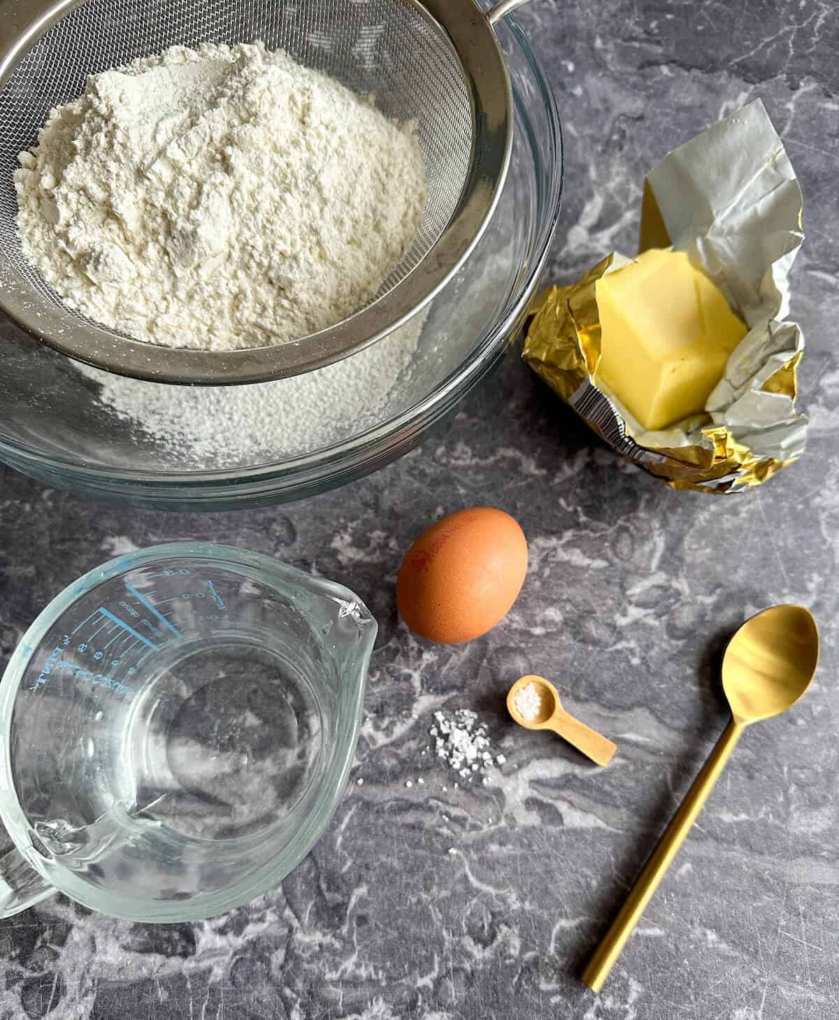 Ingredients for shortcrust pastry on a table. All-purpose flour, unsalted butter, egg yolk, water and salt. 
