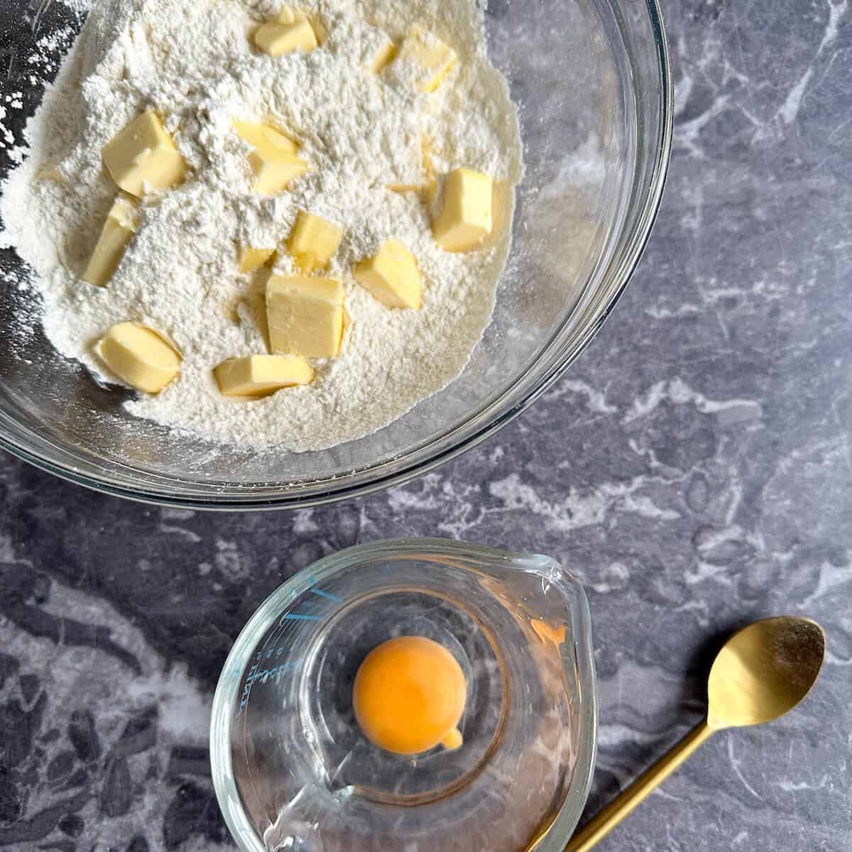 A large mixing bowl with flour and chunks of butter in it.