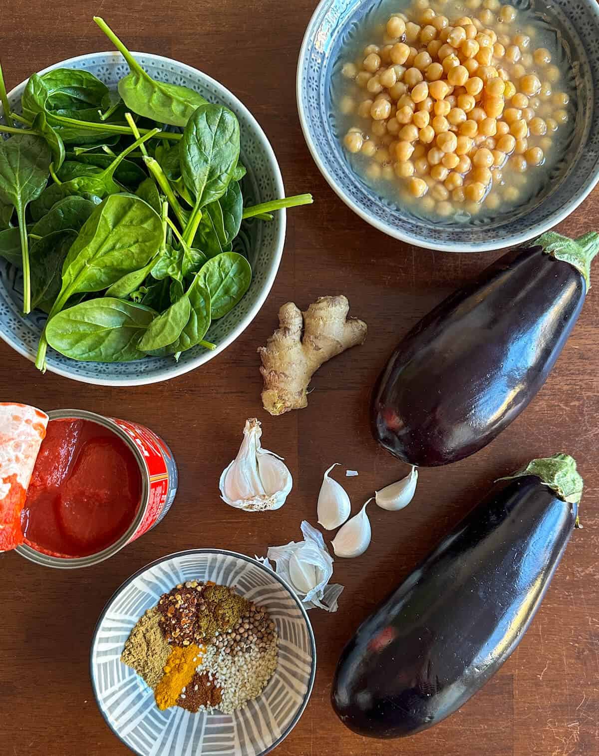 Ingredients for eggplant masala: aubergine or eggplant, chickpeas, tinned tomatoes, garlic, ginger, spinach and a spice mix made from garam masala, cumin, fennel seeds, coriander seeds, cumin, turmeric, cayenne pepper and chilli flakes. 