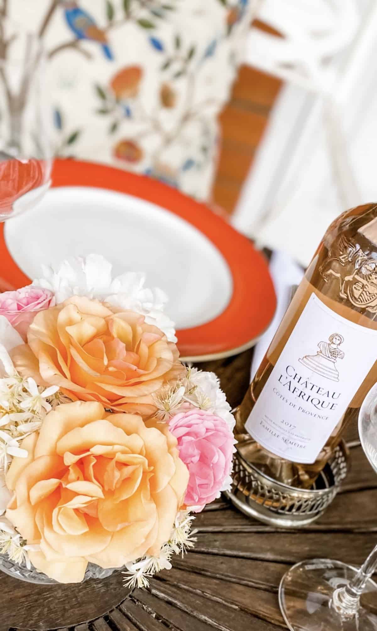 A bottle of rose wine on a table laid with fresh summer flowers.