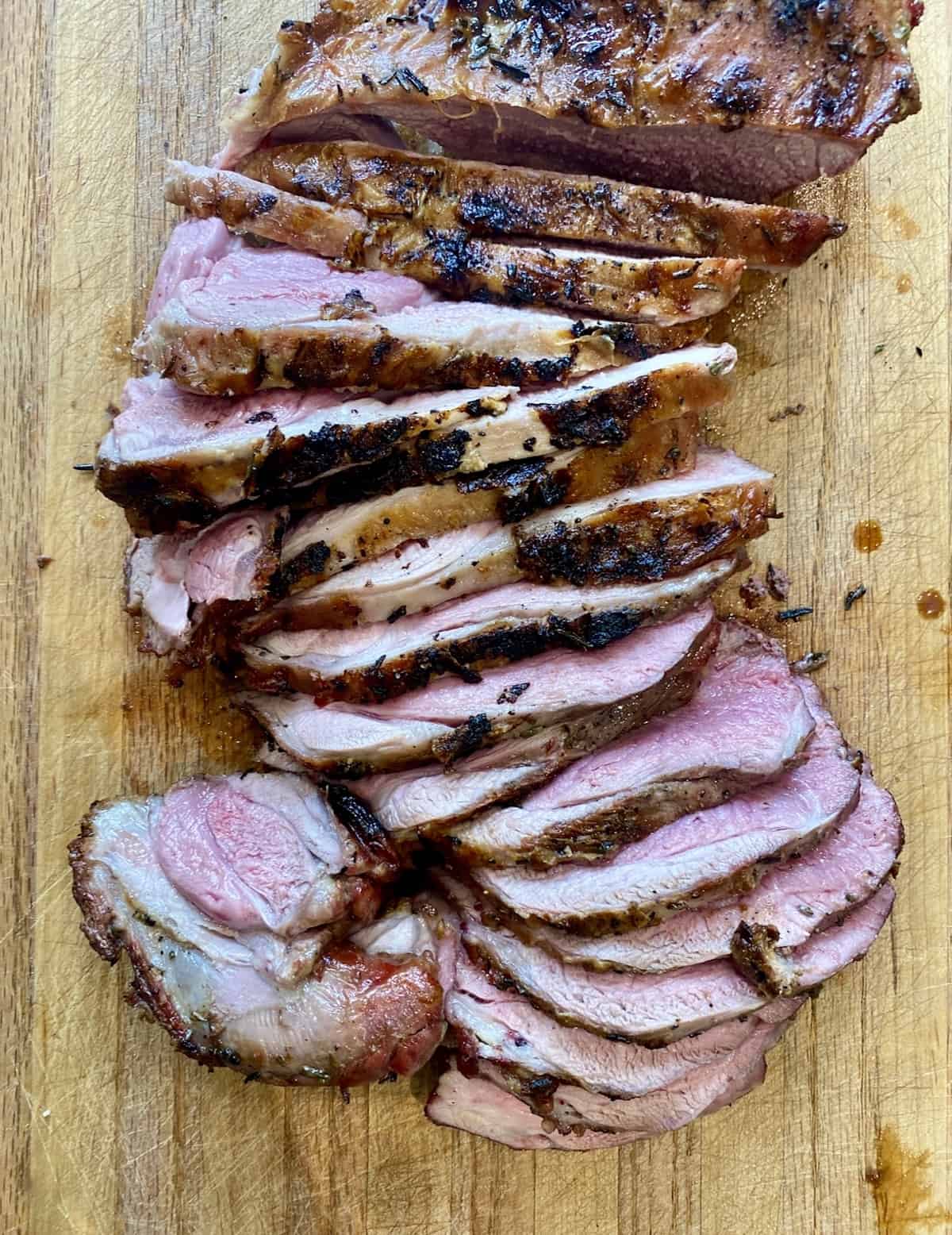 Image shows sliced lamb on a wooden chopping board. Find food and wine pairing tips to serve the right glass of wine with red meat. 