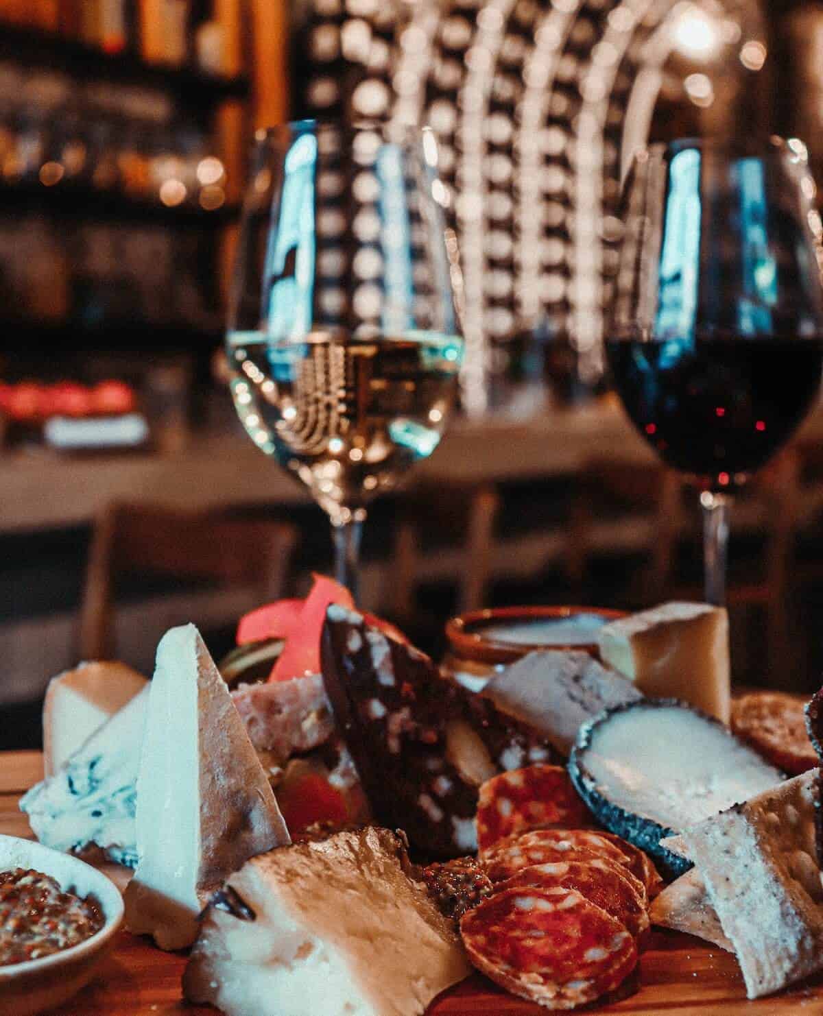 Two glasses of wine and a cheeseboard on a table. 